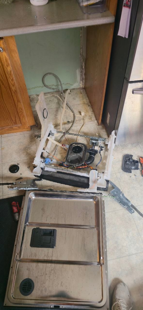 Built-in dishwasher removed from the cabinet with the circulation pump, wash module, and spray arm assembly exposed on the kitchen floor during repair by Caspian Appliance Repair Hamilton