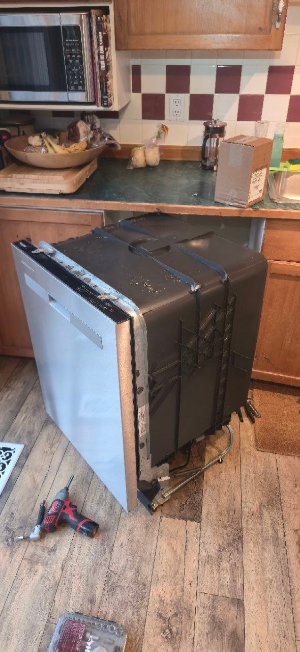 Built-in dishwasher pulled out and tilted to access the base and bottom panel during a leak repair by a Caspian Appliance Repair technician in Hamilton, Ontario