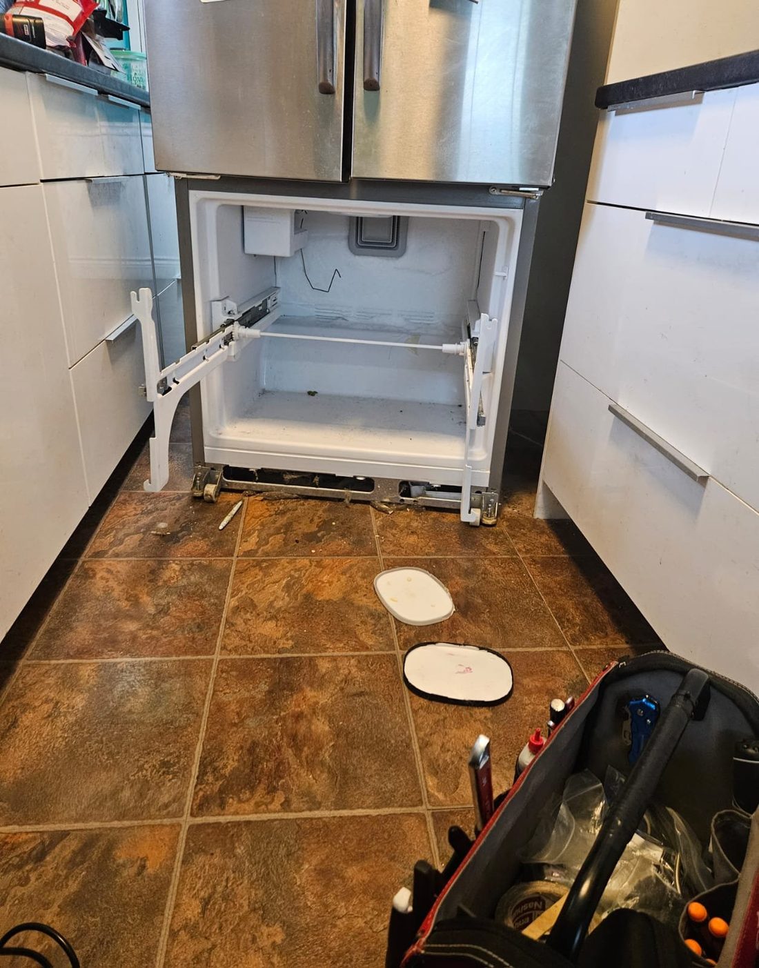 Caspian technician repairing a French-door refrigerator with the freezer drawer removed in a Hamilton, Ontario kitchen