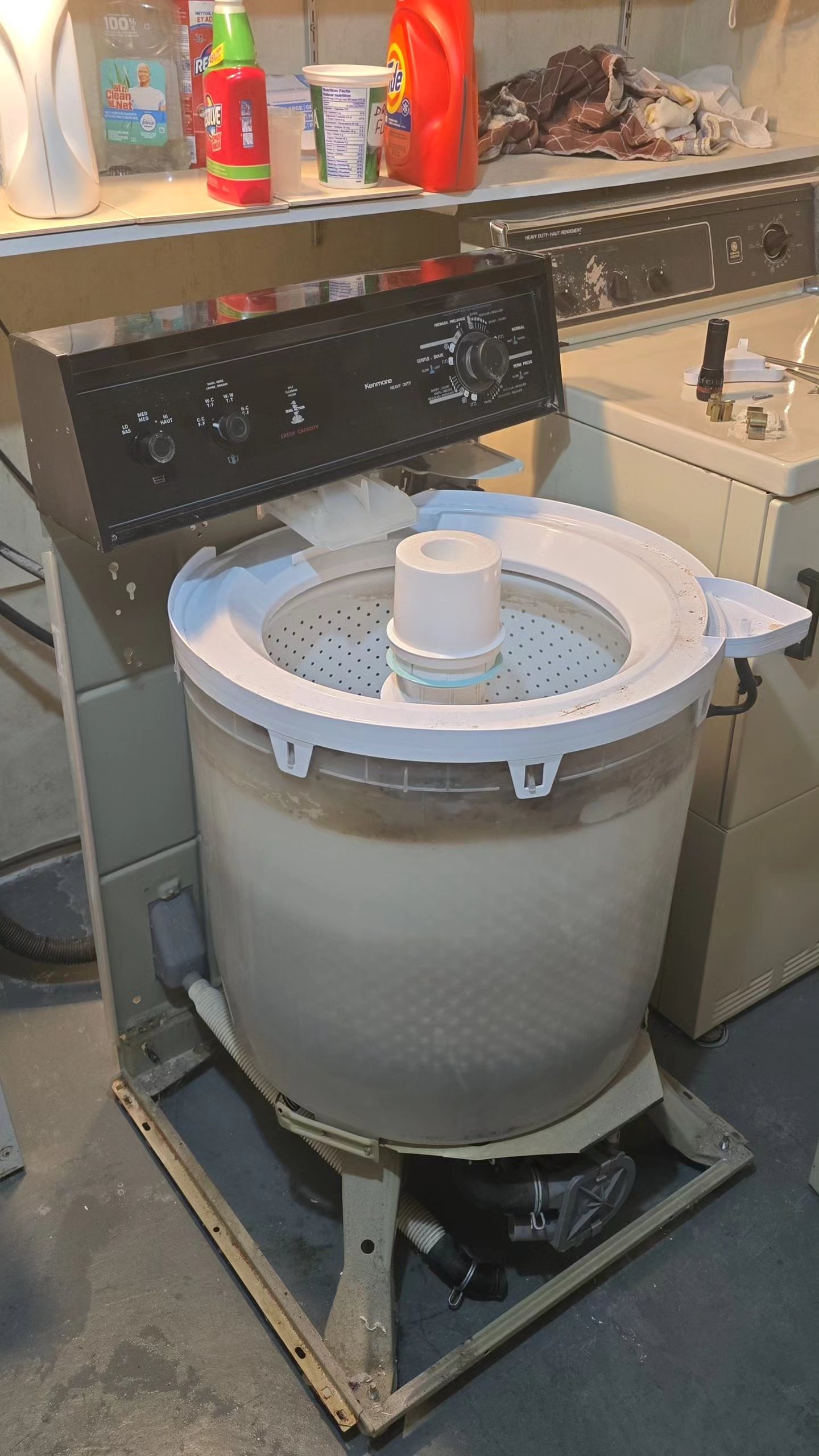 Vintage Kenmore top-load washing machine with cabinet lifted exposing inner tub during motor coupling replacement in a Hamilton, Ontario basement laundry