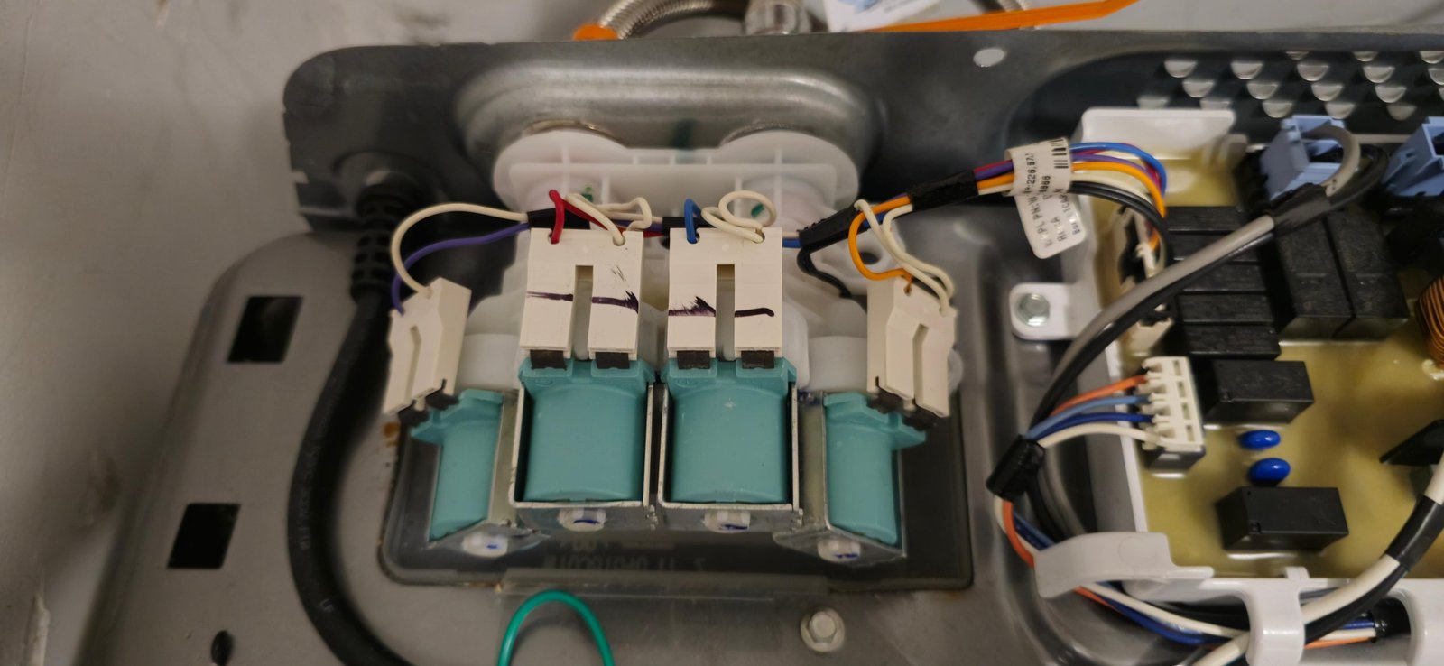 Close-up of LG top-load washing machine water inlet valve assembly with four solenoid valves during replacement service by Caspian Appliance Repair Hamilton