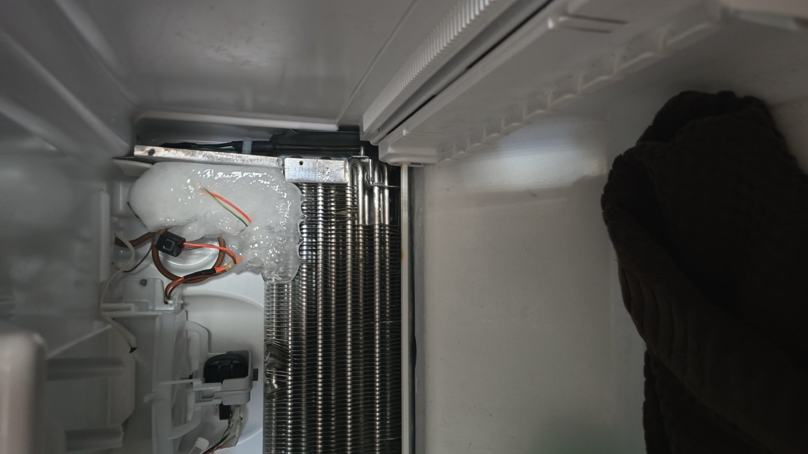 Ice buildup on refrigerator evaporator coil indicating defrost system failure, diagnosed by Caspian Hamilton technician