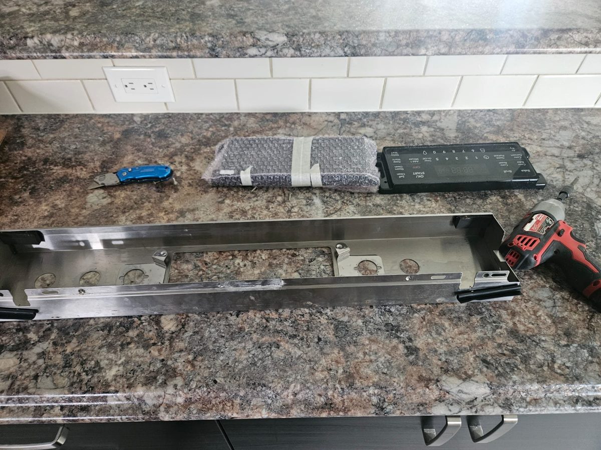 Range control panel removed with the electronic control board detached during a control board replacement by Caspian Appliance Repair in Hamilton, Ontario